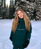 Woman wearing Nexarina Indy snow jacket in emerald green, front view outdoors