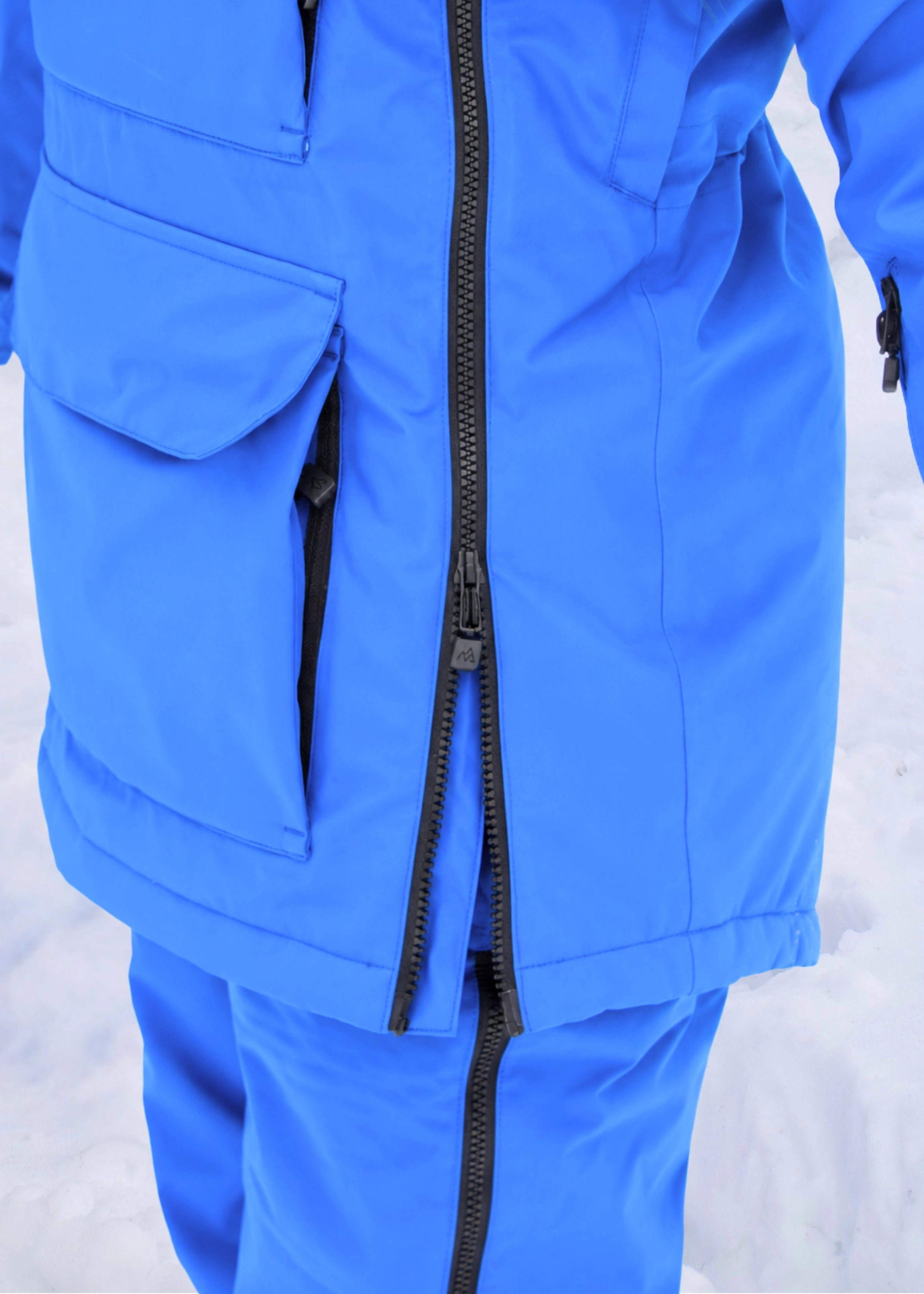 Close-up of Nexarina Indy Arctic Blue ski jacket showing the two-way side zipper and lower front pocket.