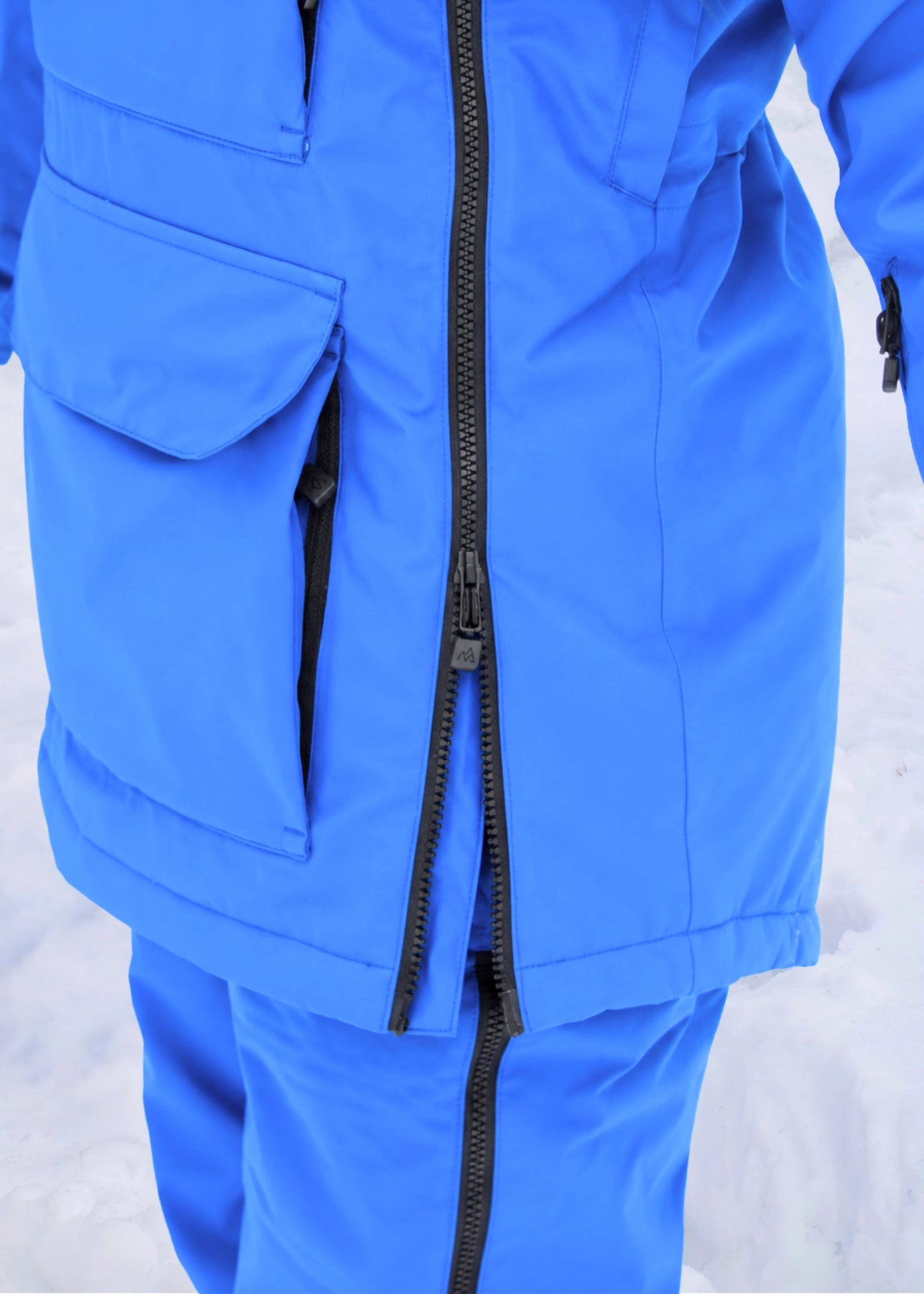 Close-up of Nexarina Indy Arctic Blue ski jacket showing the two-way side zipper and lower front pocket.