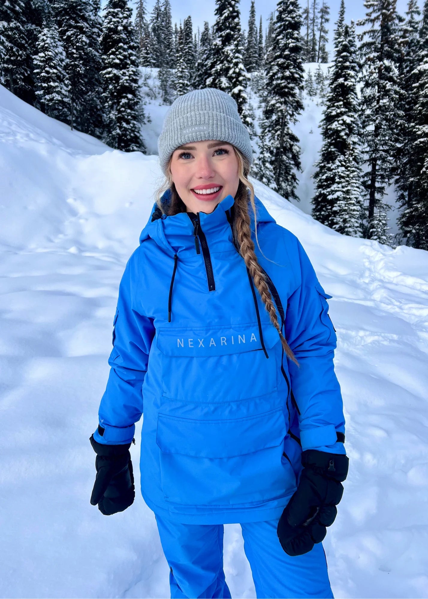 Person wearing a blue snowsuit with 'Nexarina' branding in a snowy landscape.