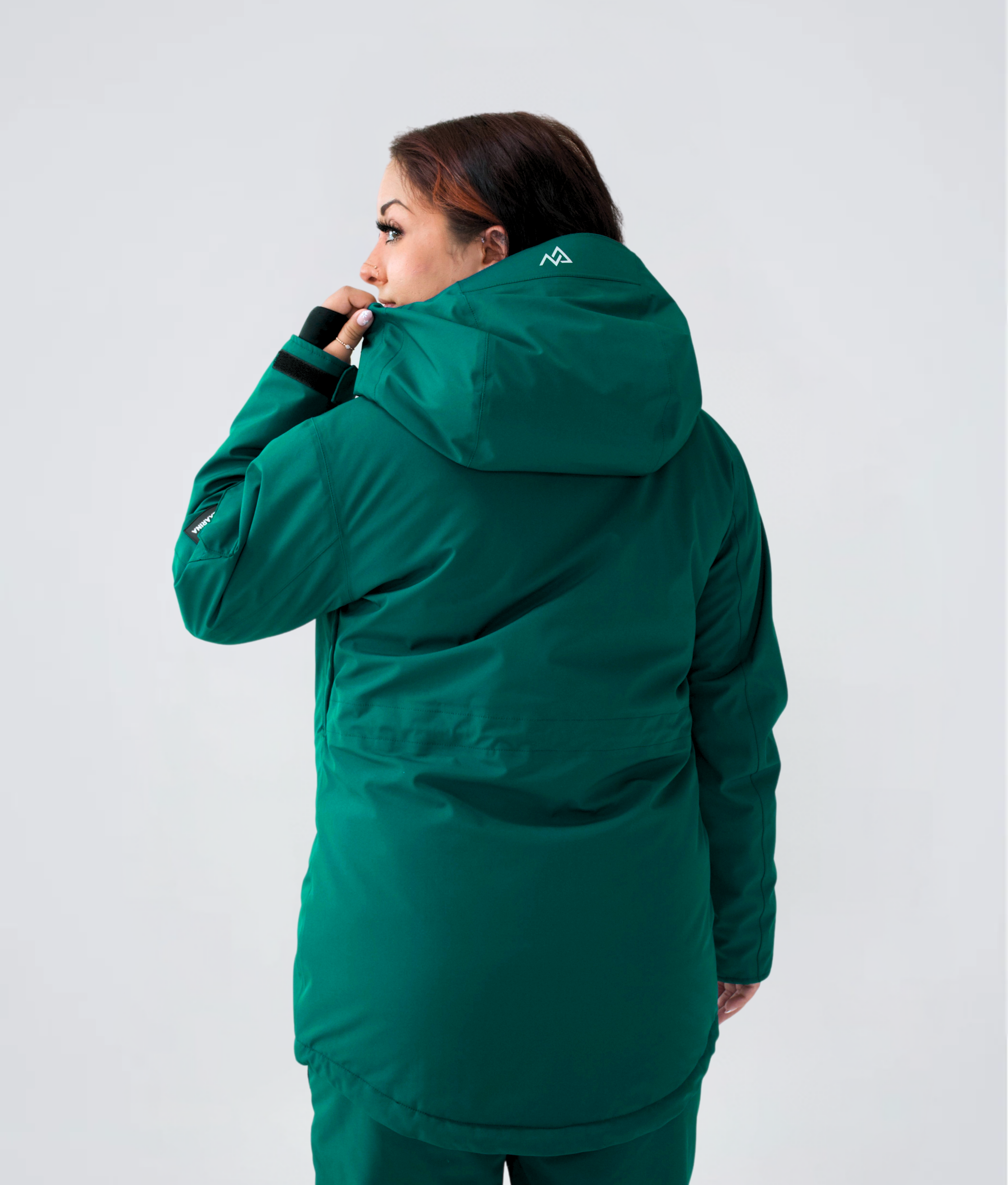 Woman showing back of Nexarina Indy Jacket in Emerald Green.