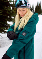 Woman wearing Nexarina Indy Emerald Green ski jacket showing the sleeve fit and winter styling.