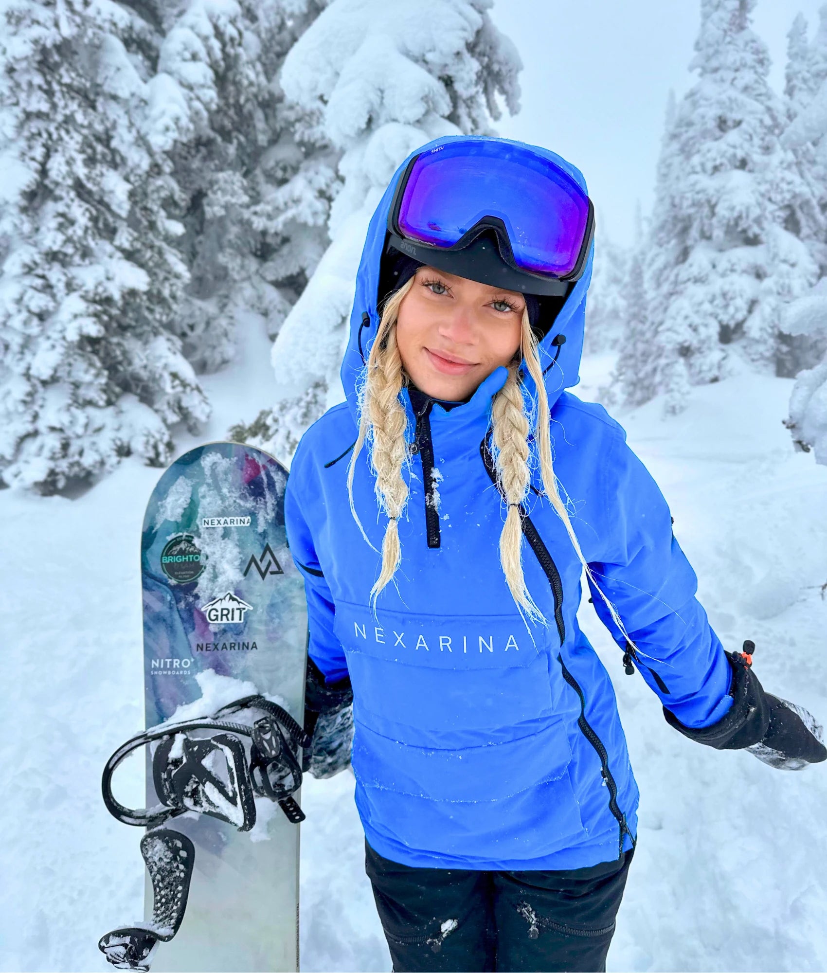 Rider wearing Nexarina Indy Snow Jacket in Arctic Blue holding a snowboard