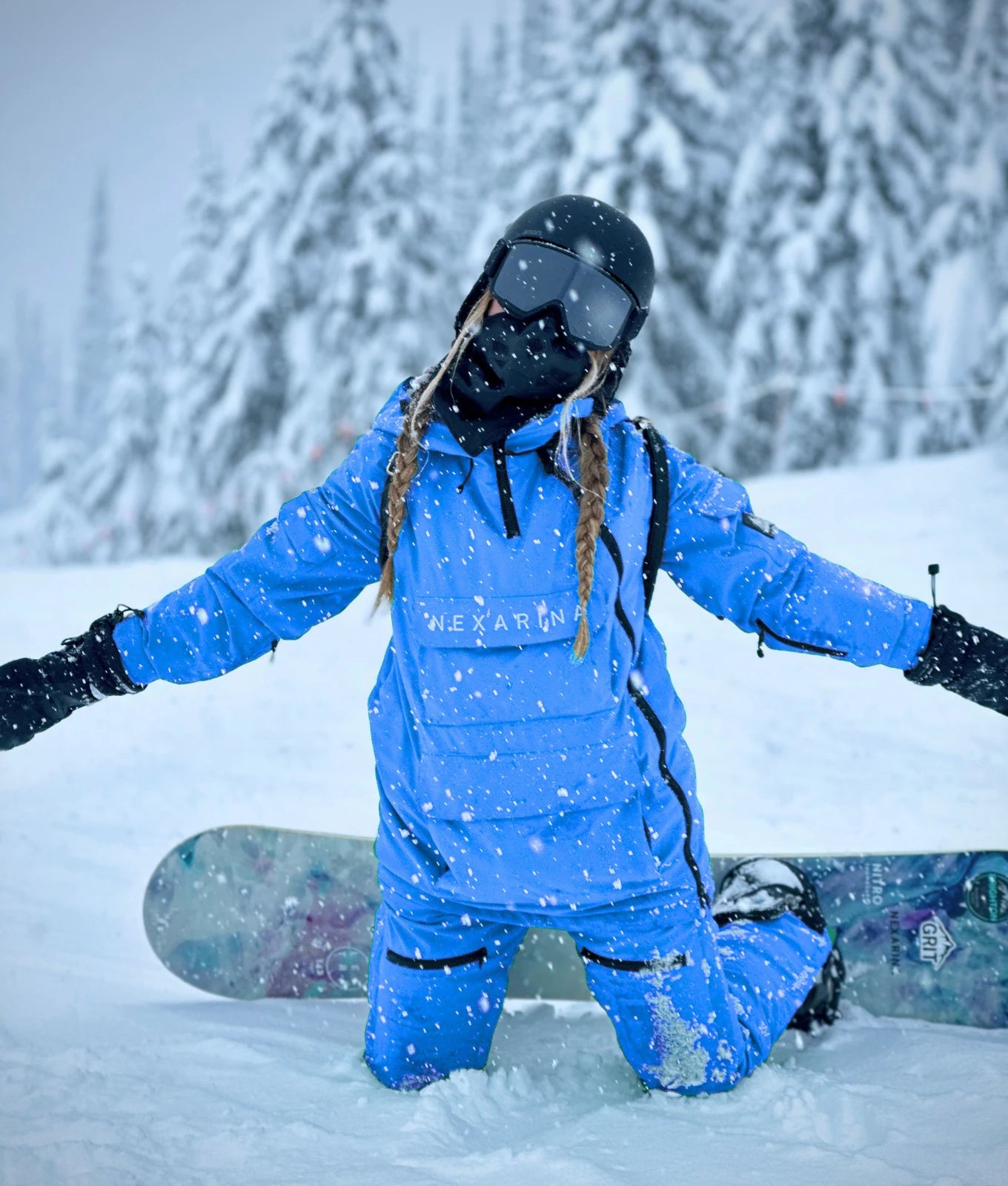 Woman kneeling in snow wearing Nexarina Indy Snow Jacket in Arctic Blue, showing fit and mobility