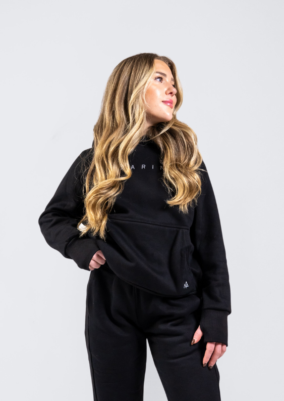Woman in Nexarina Midnight Black Hoodie smiling and looking sideways.