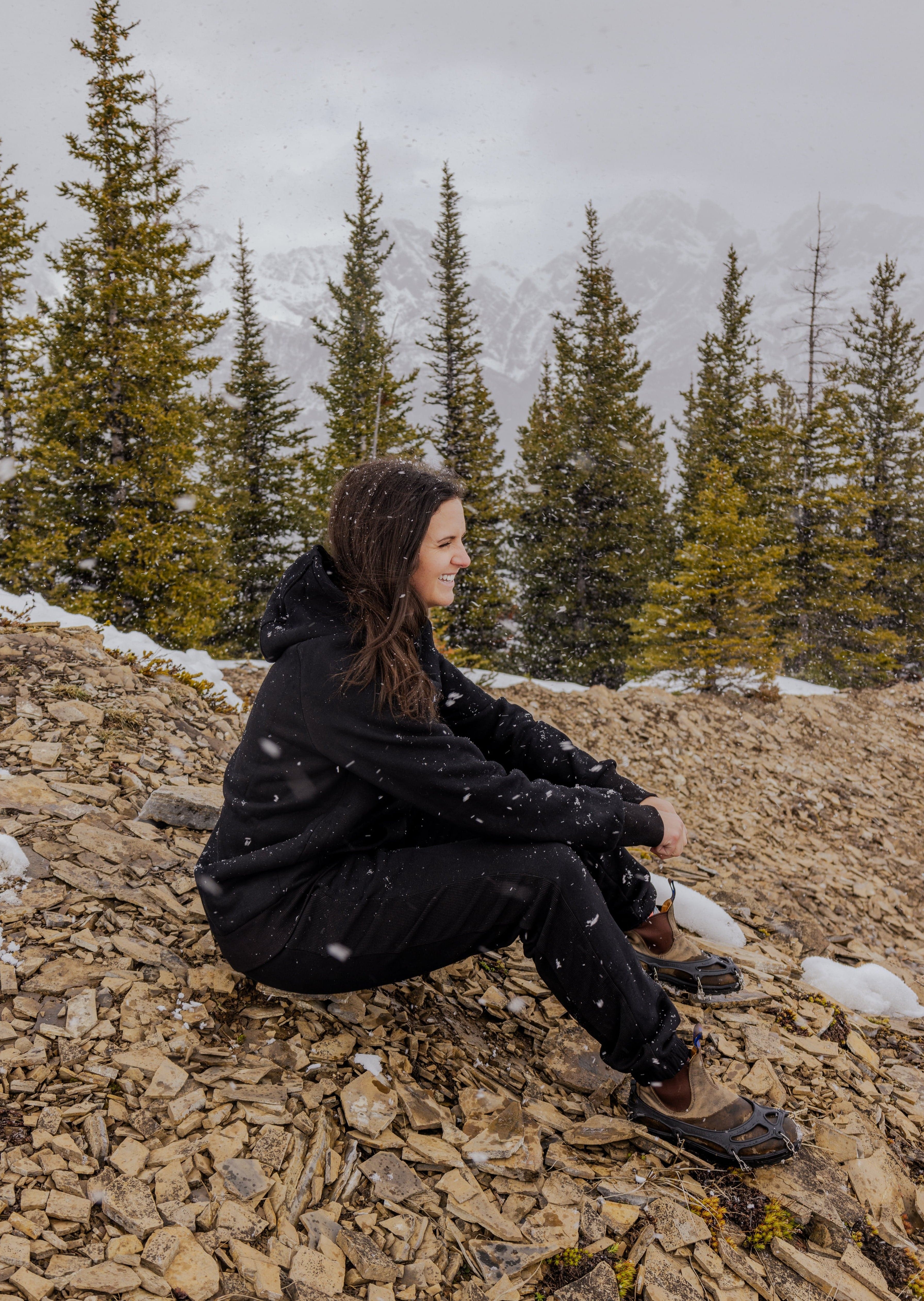 Woman wearing Nexarina Midnight Black Hoodie sitting on a mountain.