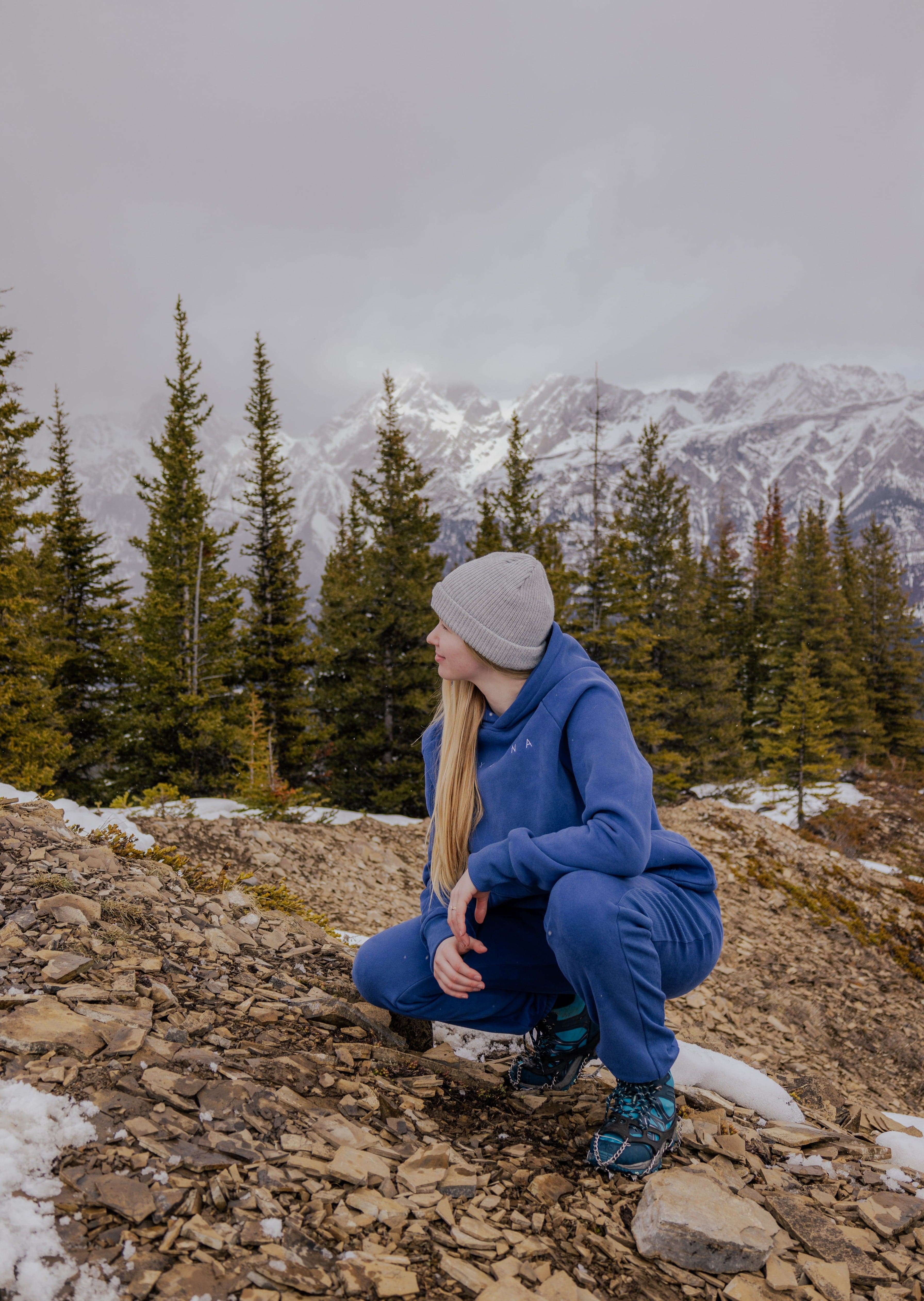 Woman wearing Nexarina Dusty Blue Hoodie in a mountain setting.