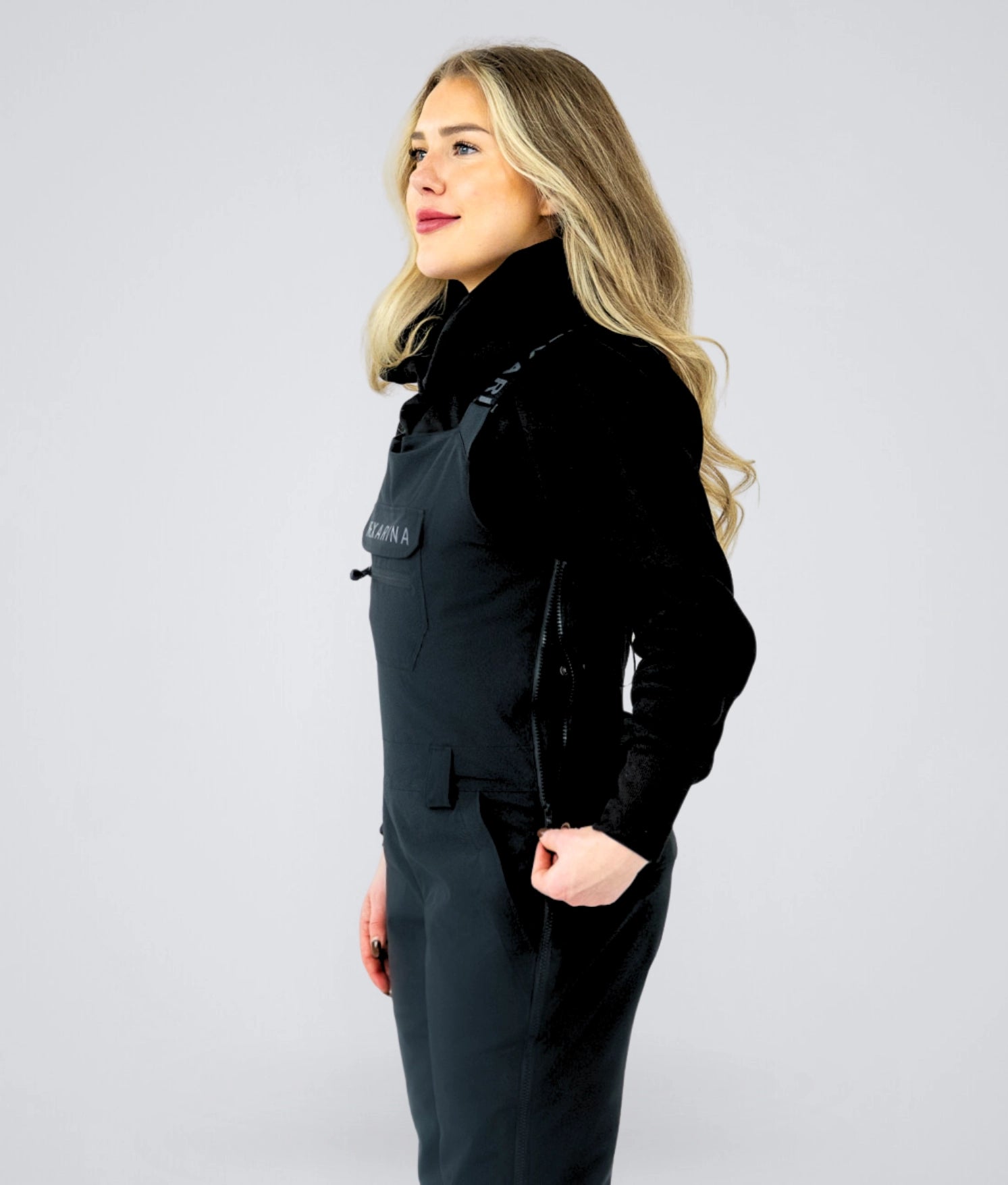 Side profile of Nexarina Everette women’s black bib snow pants with streamlined bib design and women’s fit.
