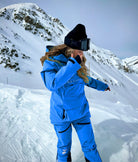  A snowboarder wears blue Avani snow pants, designed for movement, warmth, and protection in winter conditions.