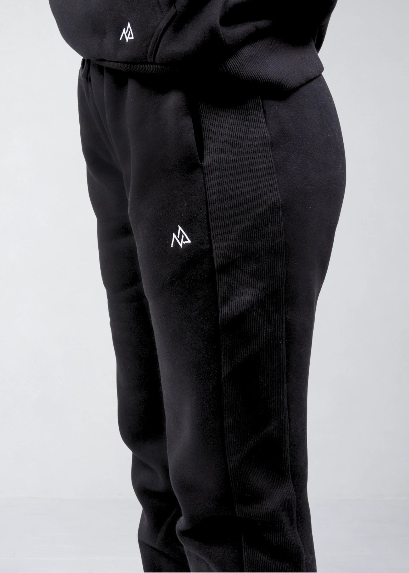 Close-up of the Nexarina logo and ribbed side panel on black sweatpants