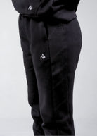 Close-up of the Nexarina logo and ribbed side panel on black sweatpants