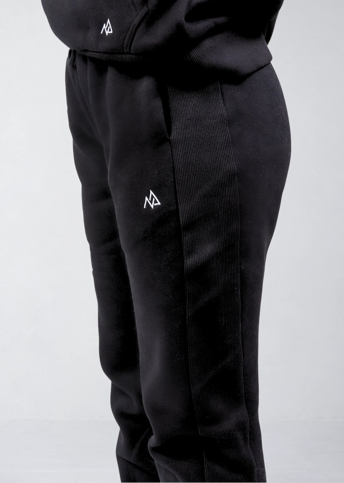 Close-up of the Nexarina logo and ribbed side panel on black sweatpants
