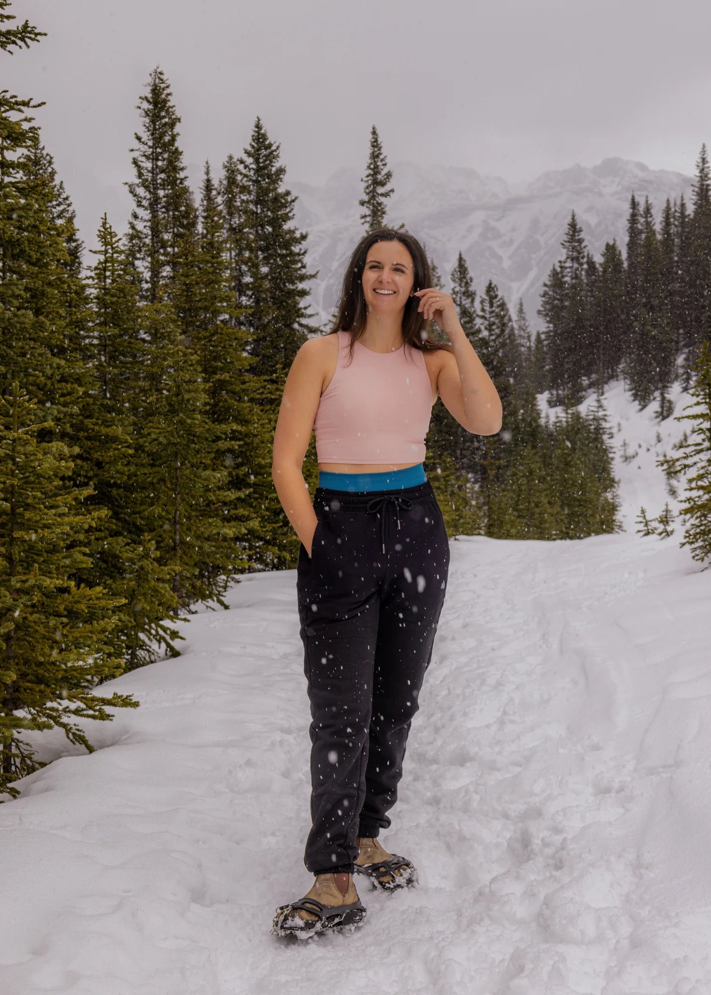 Woman wearing Nexarina Willow Sweatpants in Midnight Black on a snowy mountain trail