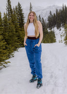 Women's Willow Sweatpants in Dusty Blue worn outdoors in the snow with a mountain backdrop.